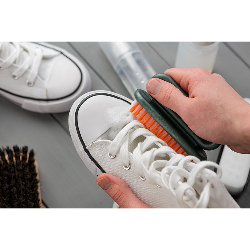 Person cleaning sneakers with brush.